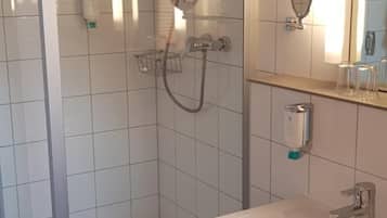Un baño moderno con ducha de vidrio, lavamanos blanco y espejo.