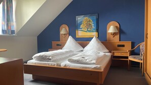A hotel room with a bed, two nightstands, a chair, and a painting on the wall. - Hotel Berghof (Nieheim)