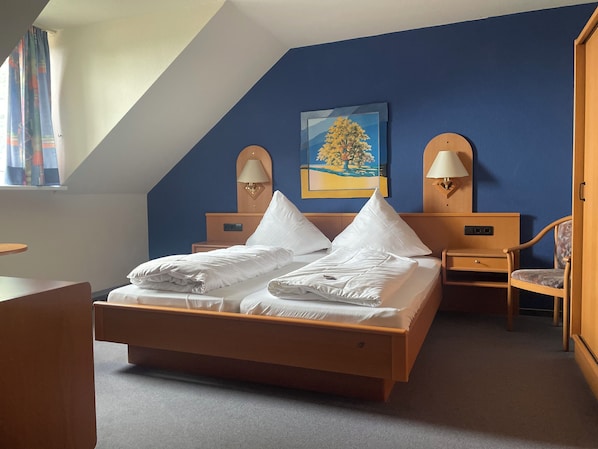 A hotel room with a bed, two nightstands, a chair, and a painting on the wall.