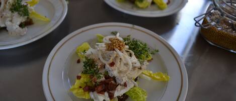 Una mesa con platos de comida, incluyendo una ensalada de lechuga, tocino y aderezo cremoso.