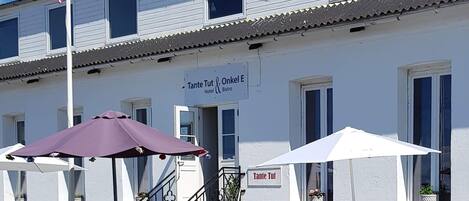 Un edificio con un letrero que dice "Tante Tut & Onkel E Hotel & Bistro" y mesas al aire libre con sombrillas.