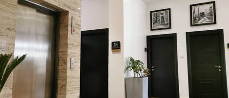 A modern lobby with a marble floor, an elevator, and three doors.