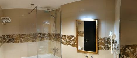 A modern bathroom with a glass-enclosed shower, a freestanding bathtub, and a gold-rimmed sink.