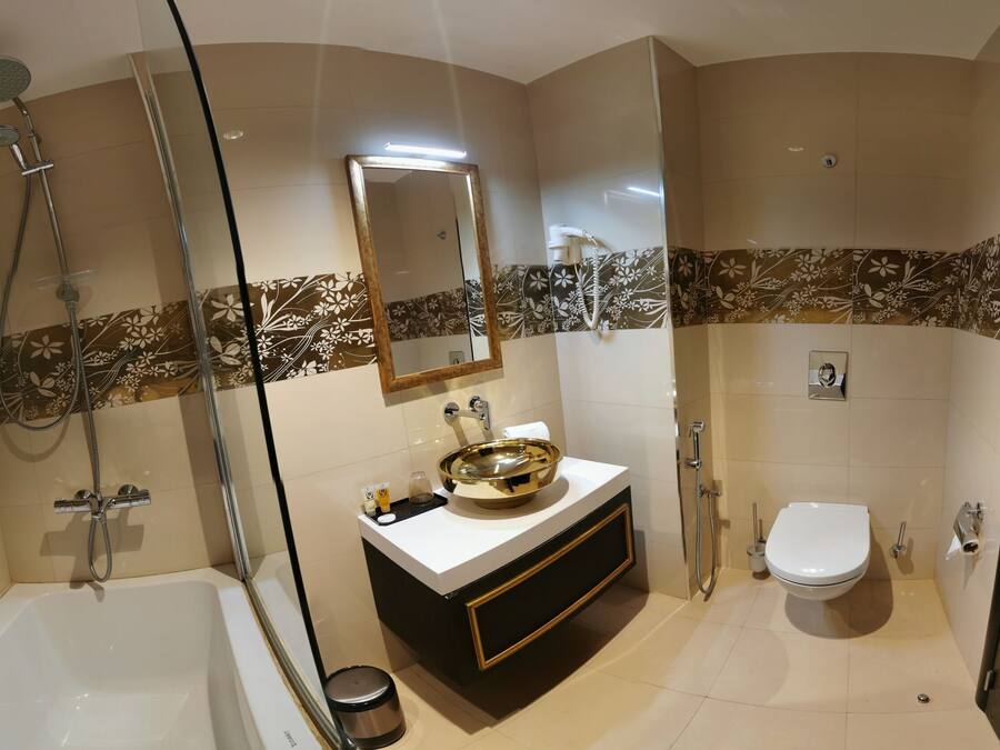 Un baño moderno con bañera, lavamanos de oro, inodoro y zona de ducha.