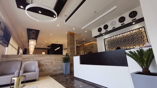 A modern reception area with a reception desk, seating area, and a decorative wall with clocks.