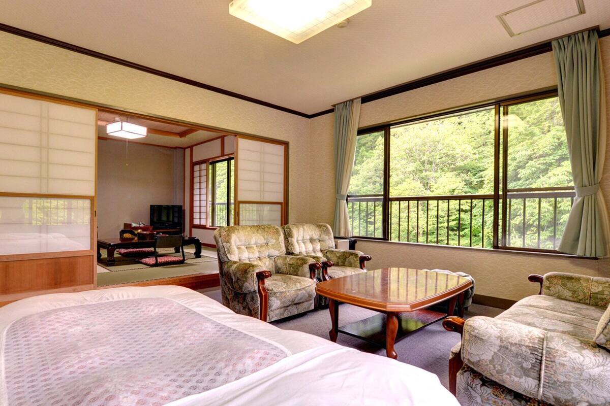 A traditional Japanese-style room with tatami flooring, a low table, and two tatami mats.
