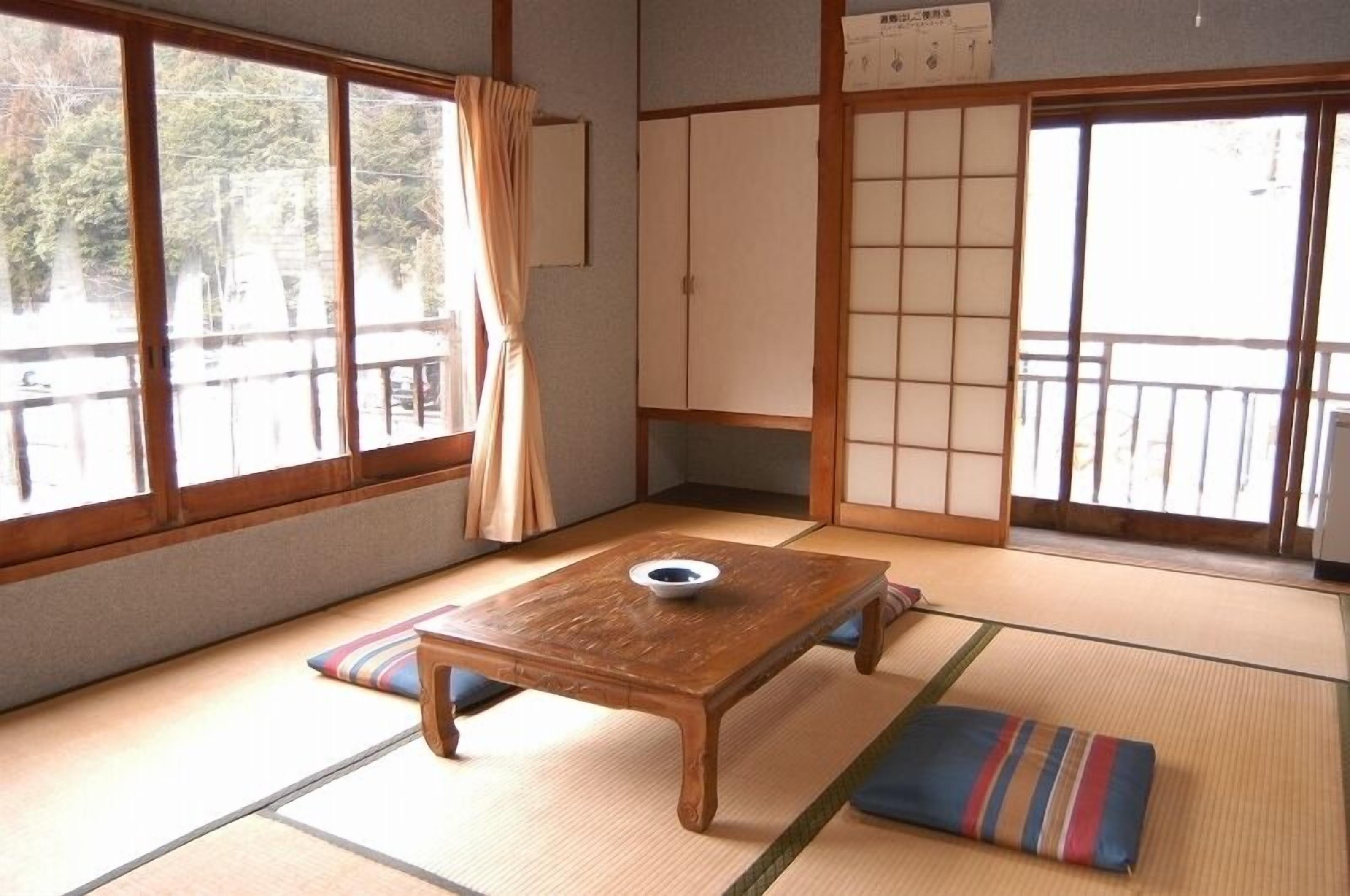 A traditional Japanese room with tatami flooring, a wooden table with a bowl, and sliding doors.