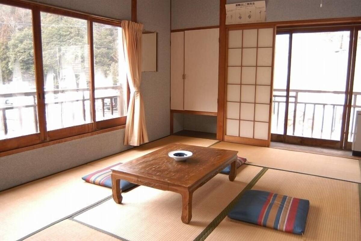 A traditional Japanese room with tatami flooring, a wooden table with a bowl, and sliding doors.