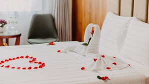 A neatly made bed with white linens and red rose petals arranged in a heart shape. - Hanoi Asia Hotel (Hanoi)
