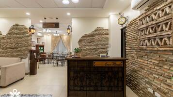 Eine Hotelhalle mit Rezeption, Treppe und Essbereich.