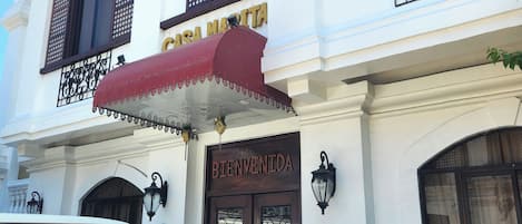 A white building with a red awning, a sign reading "CASA MARTITA," and a "BIENVENIDA" sign at the entrance.