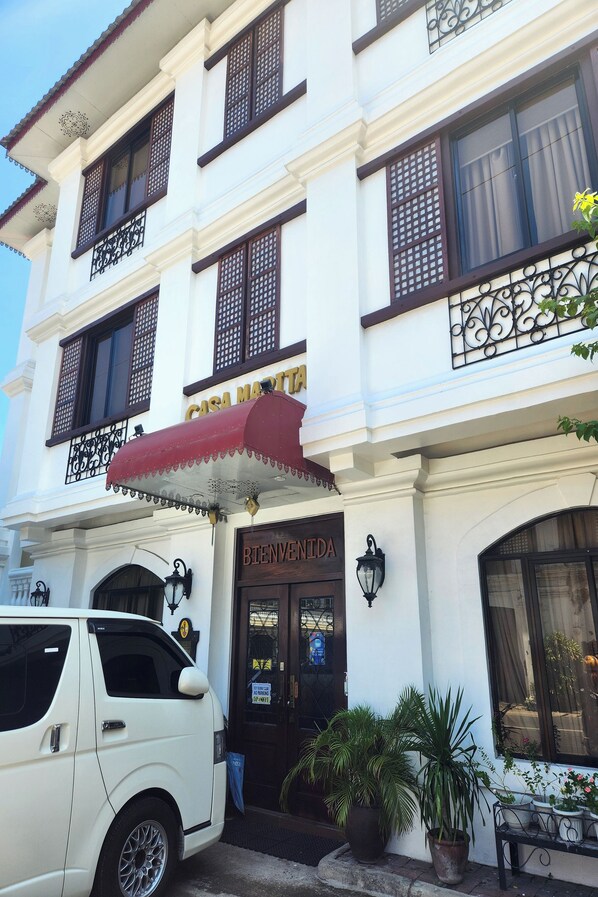 A white building with a red awning, a sign reading "CASA MARTITA," and a "BIENVENIDA" sign at the entrance. - Casa Marita Vigan By Zuzu (Vigan)