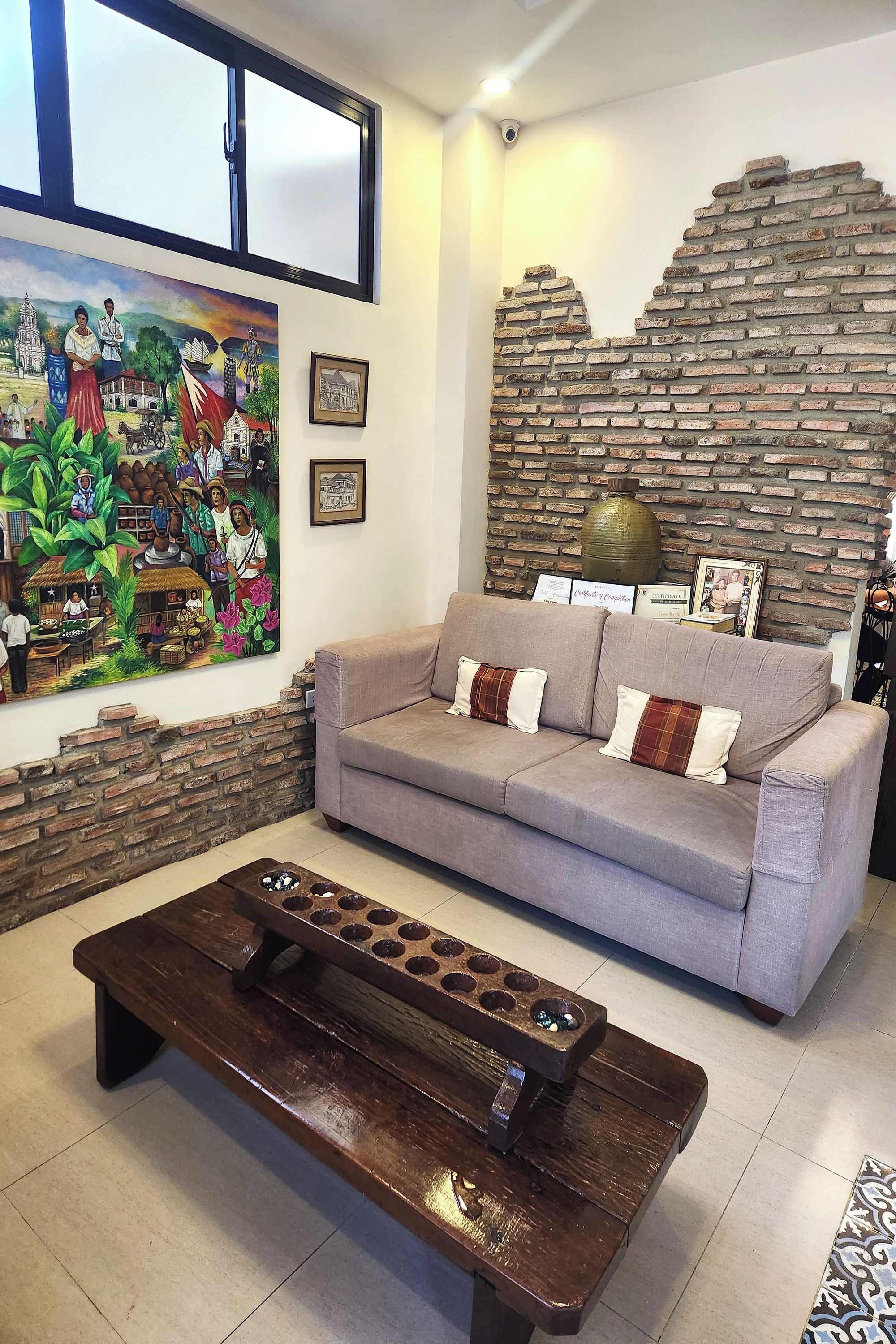 A living room with a sofa, a coffee table, a mural, and a brick wall.