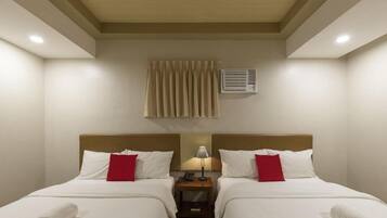 Ein Hotelzimmer mit zwei Betten, einem Nachttisch mit Lampe und einer Klimaanlage an der Wand.
