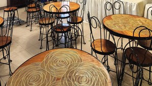 A dining area with round tables, chairs, a buffet setup, a television, and a ceiling fan.