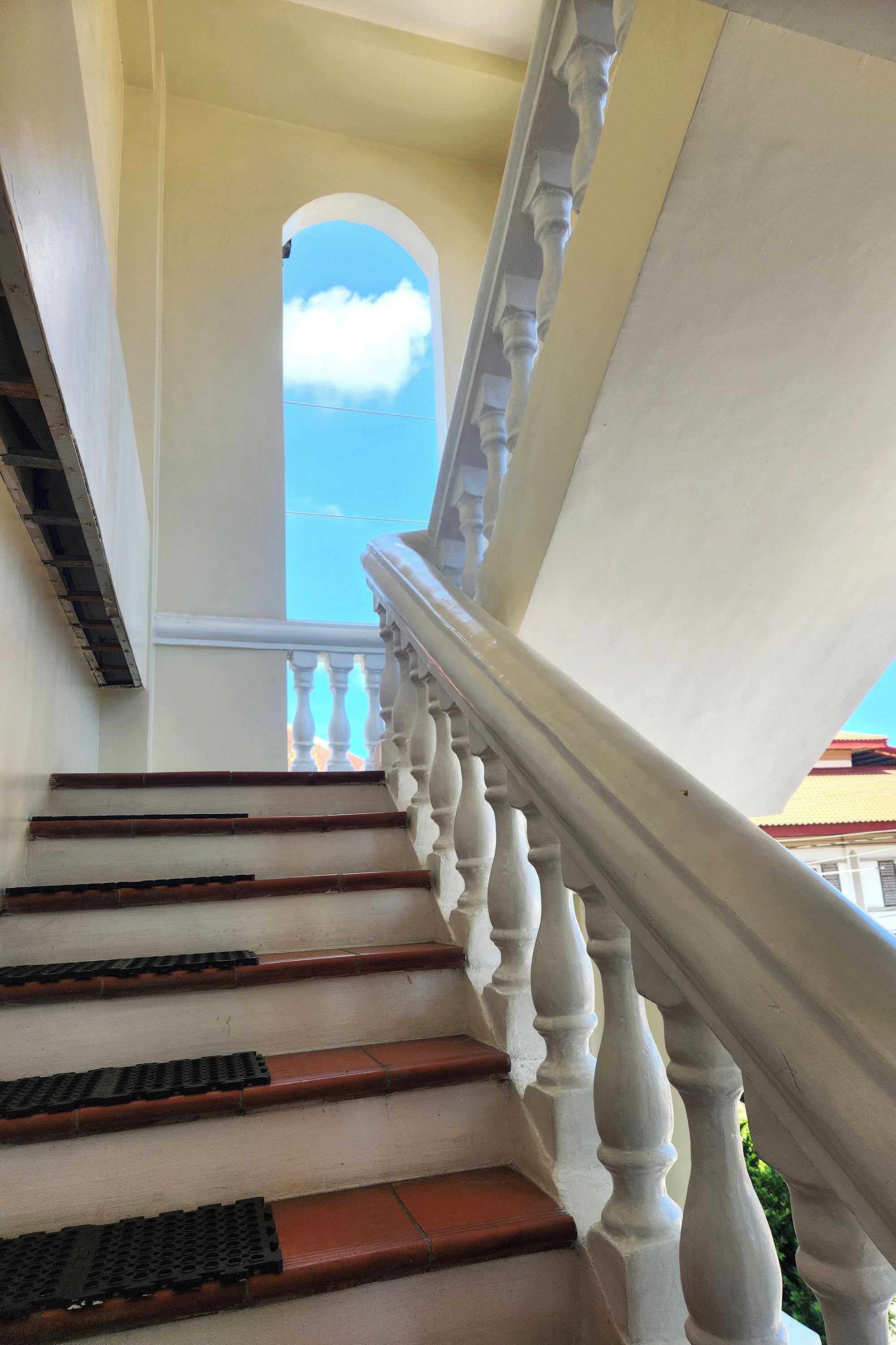 A staircase with white balustrades and red steps leading to an arched doorway.