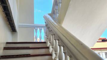 A staircase with white balustrades and red steps leading to an arched doorway.