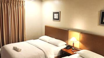 A hotel room with two beds, a nightstand with a lamp, an air conditioner, and a framed picture on the wall.