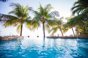 A pool surrounded by palm trees and a statue. - Teluk Indah Beach & Pool Villa (Tejakula)