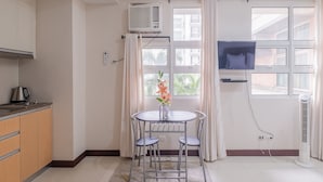Une petite cuisine avec une table à manger, des chaises et un téléviseur fixé au mur.