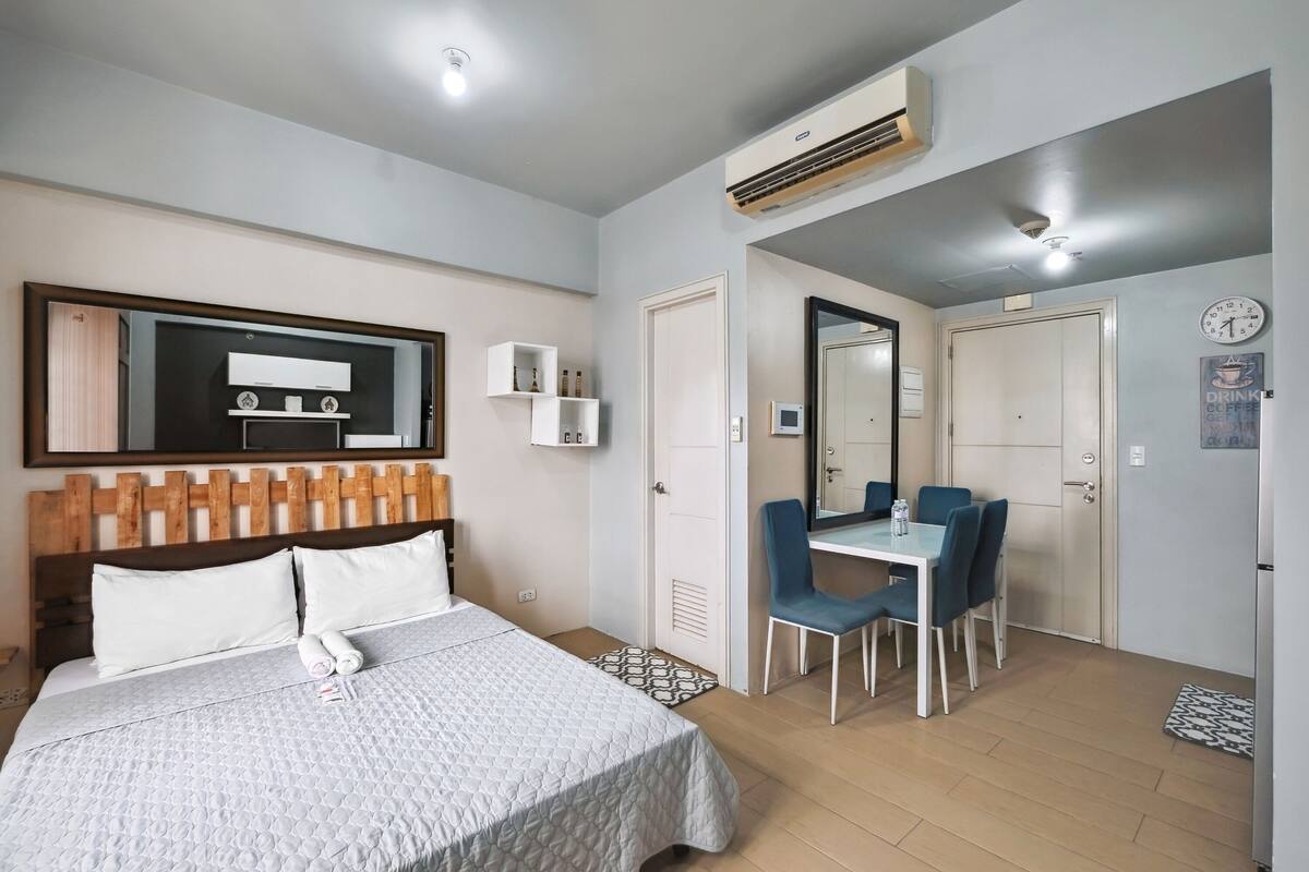 Habitació d'hotel amb llit, escriptori i cadira. Hi ha un mirall sobre l'escriptori i un rellotge a la paret.