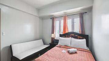 Un dormitorio con cama, un banco, una mesita de noche y una ventana con cortinas.