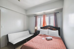 A bedroom with a bed, a bench, a nightstand, and a window with curtains.