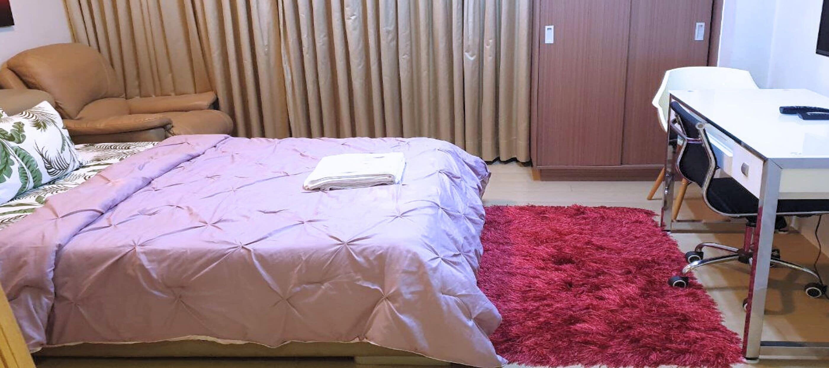 Een slaapkamer met een bed, een bureau en een stoel.