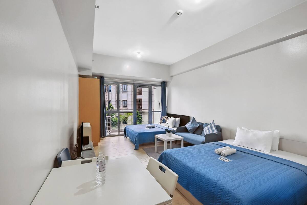 Habitació d'hotel amb un llit, un sofà, un escriptori i una finestra.