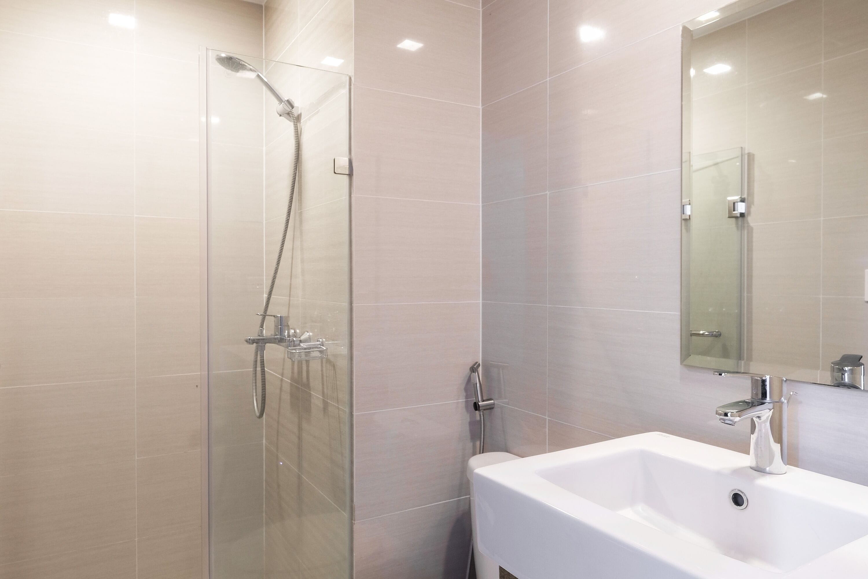 A modern bathroom with a glass-enclosed shower, a white sink, and a large mirror.