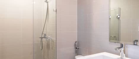 A modern bathroom with a glass-enclosed shower, a white sink, and a large mirror.