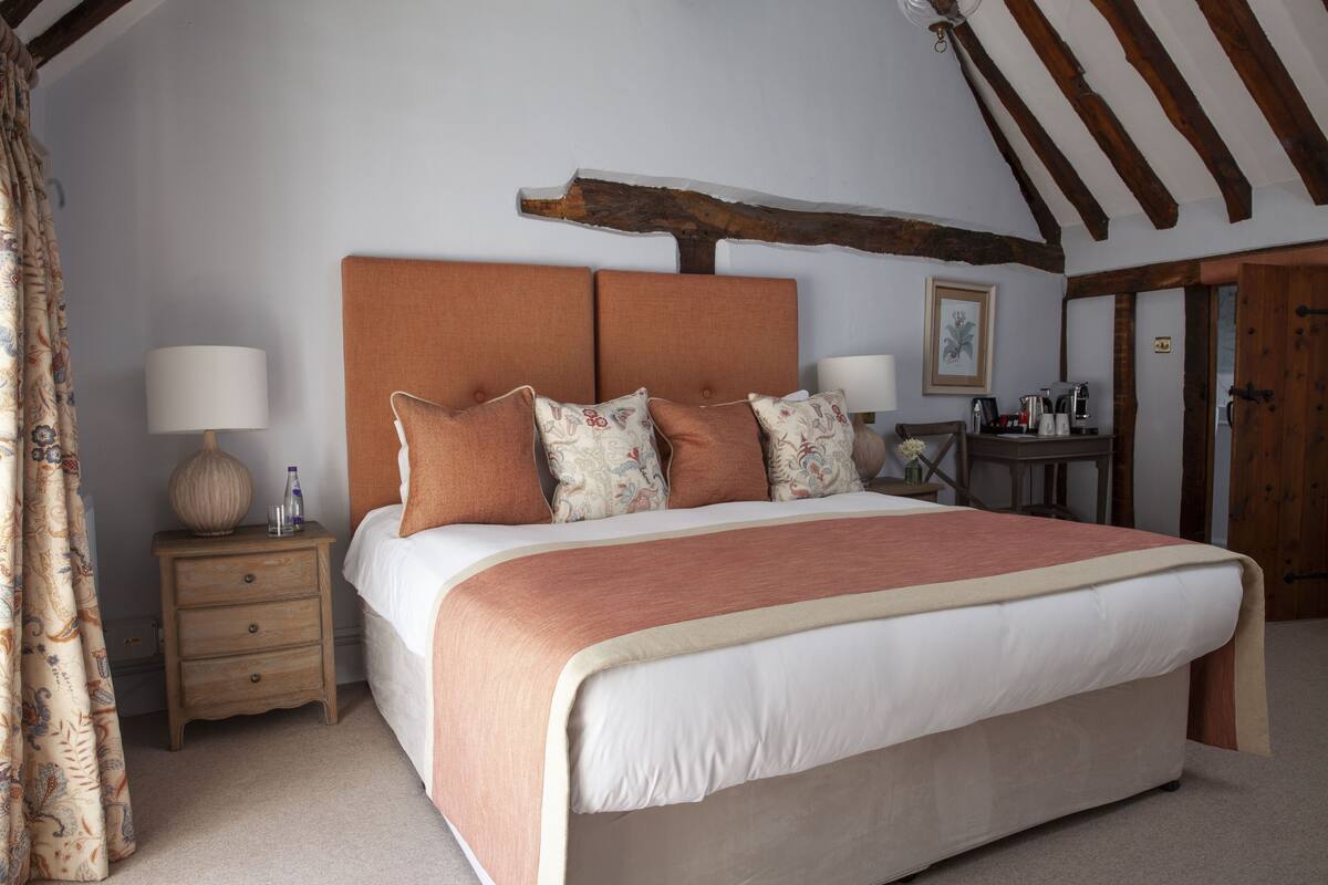 A bedroom with a large bed, wooden headboard, bedside tables, and a nightstand.