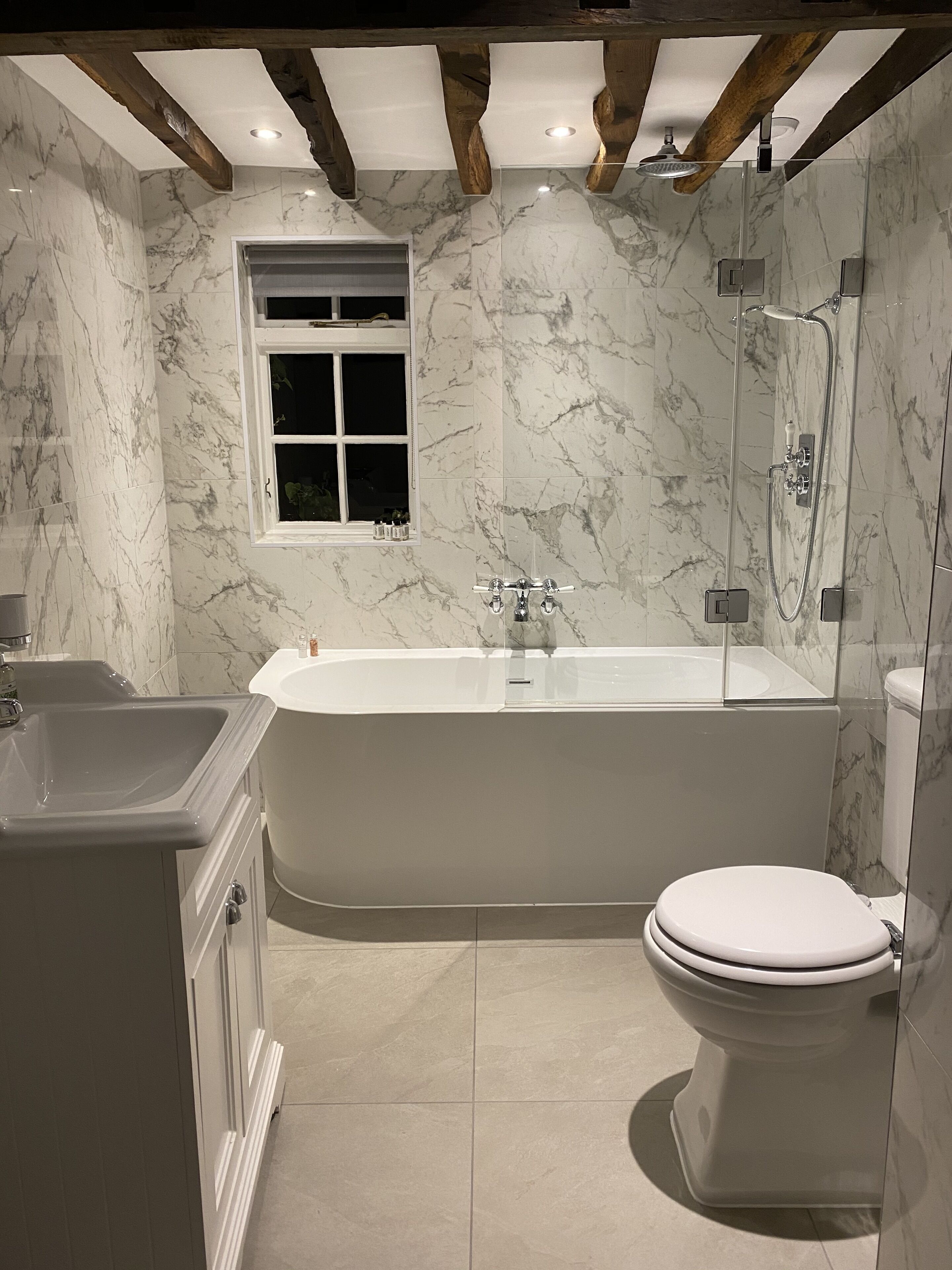 A modern bathroom with a freestanding bathtub, a toilet, and a window.