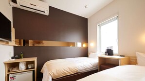 Ein Hotelzimmer mit zwei Betten, einem Schreibtisch, einer Minibar, einem Fernseher und einem Fenster mit Tageslicht.