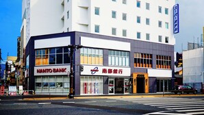 Ein mehrstöckiges Hotel mit moderner Fassade, mit gut sichtbarer Beschilderung für 'Super Hotel' und 'Nanto Bank' im Erdgeschoss.