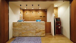 Ein Empfangsschalter mit einer Granit-Theke, Pendelleuchten an der Decke und einem digitalen Kiosk.