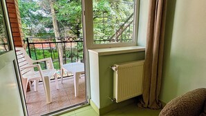 A room with a view of a garden, a radiator, a window with curtains, and a sofa. - Agio Hotel (Kolochava)