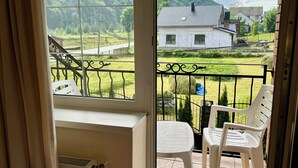 Una habitación con vistas a un paisaje verde, un balcón con mesa y sillas, y un radiador.