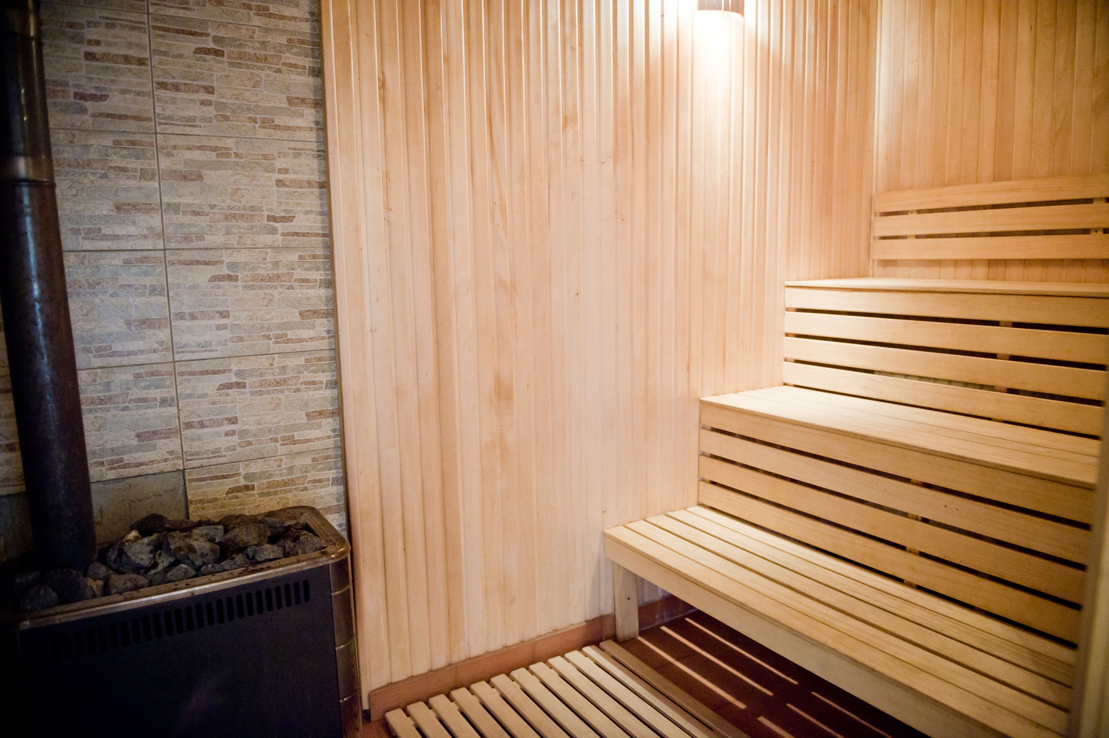 A sauna with wooden benches and a stone wall.