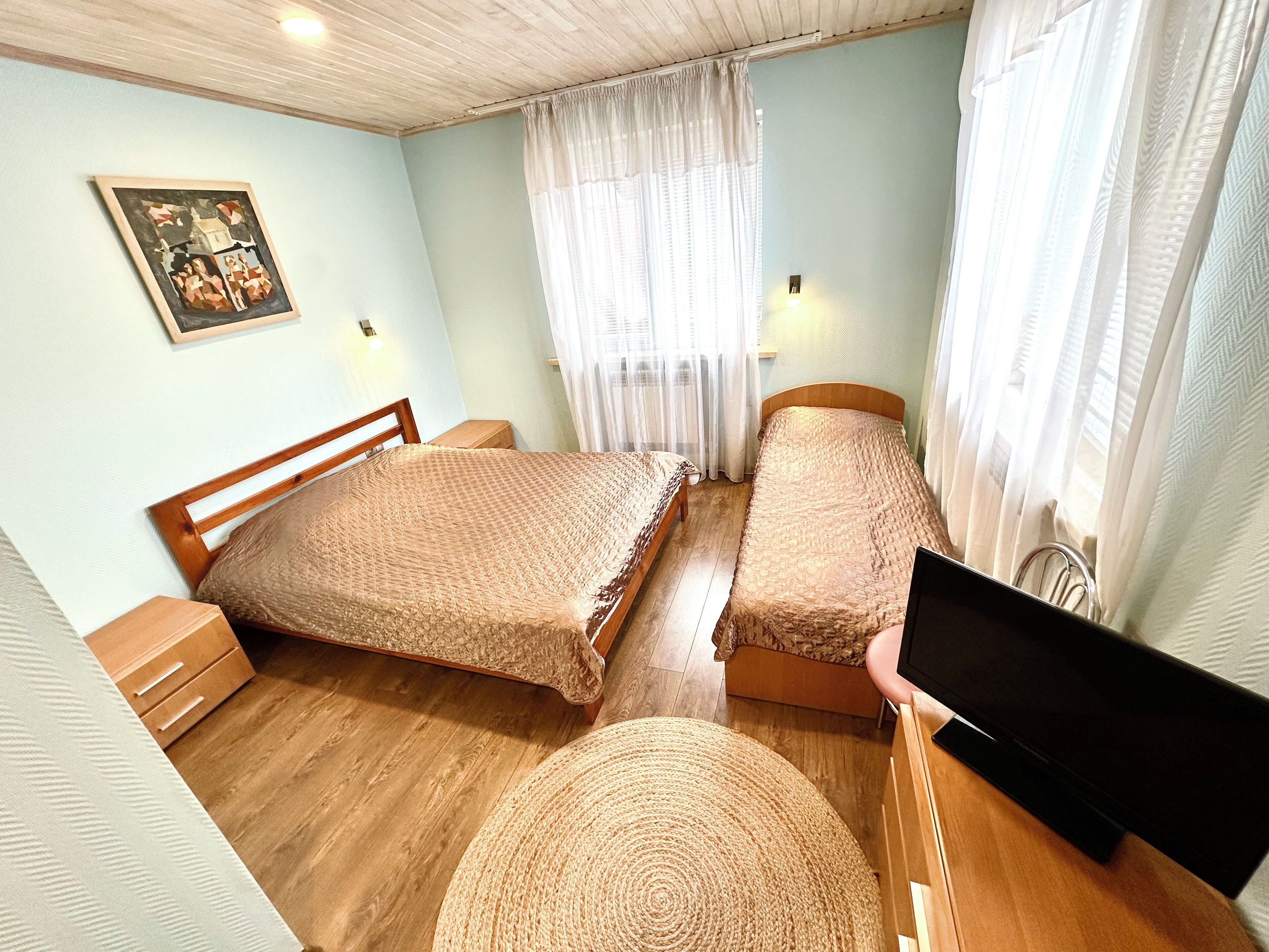A bedroom with two beds, a television, and a painting on the wall.