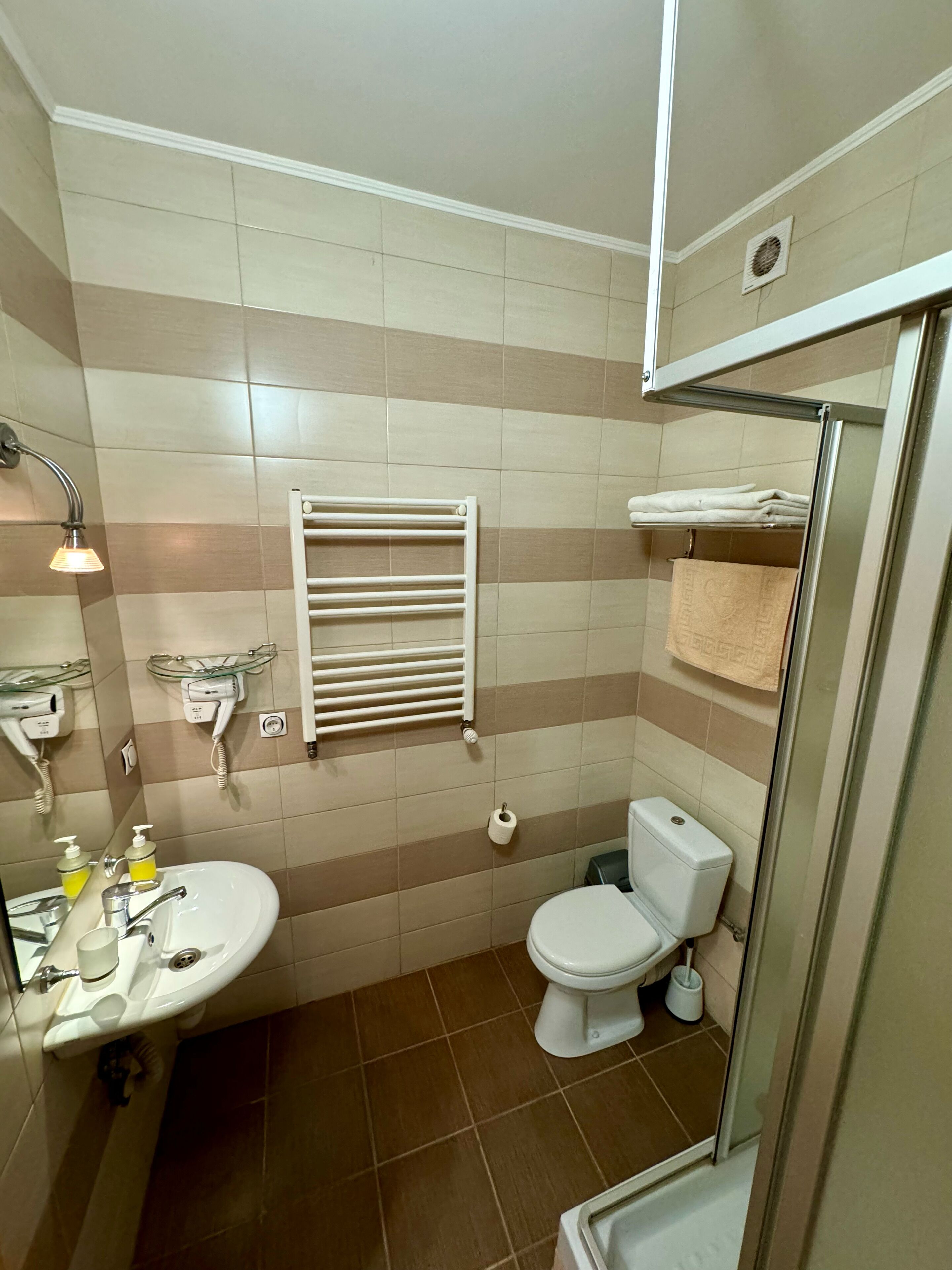A bathroom with a sink, toilet, towel rack, and a glass shower enclosure.