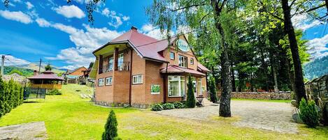 A two-story brick house with a red roof, a balcony, and a paved driveway.
