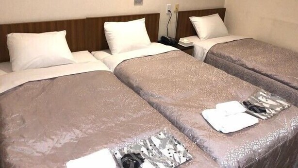 Hotellihuone, jossa on kaksi erillistä sänkyä, ja molemmissa on kuviollinen peitto ja valkoiset tyynyt. Huoneessa on yöpöytä, jossa on lamppu ja puhelin.