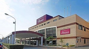 A modern building with a prominent 'Amandi' sign, a covered entrance, and a clear sky.