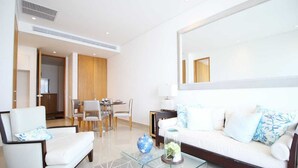 Una sala de estar moderna con un sofá, sillones, una mesa de centro de vidrio y un comedor con sillas y una mesa.