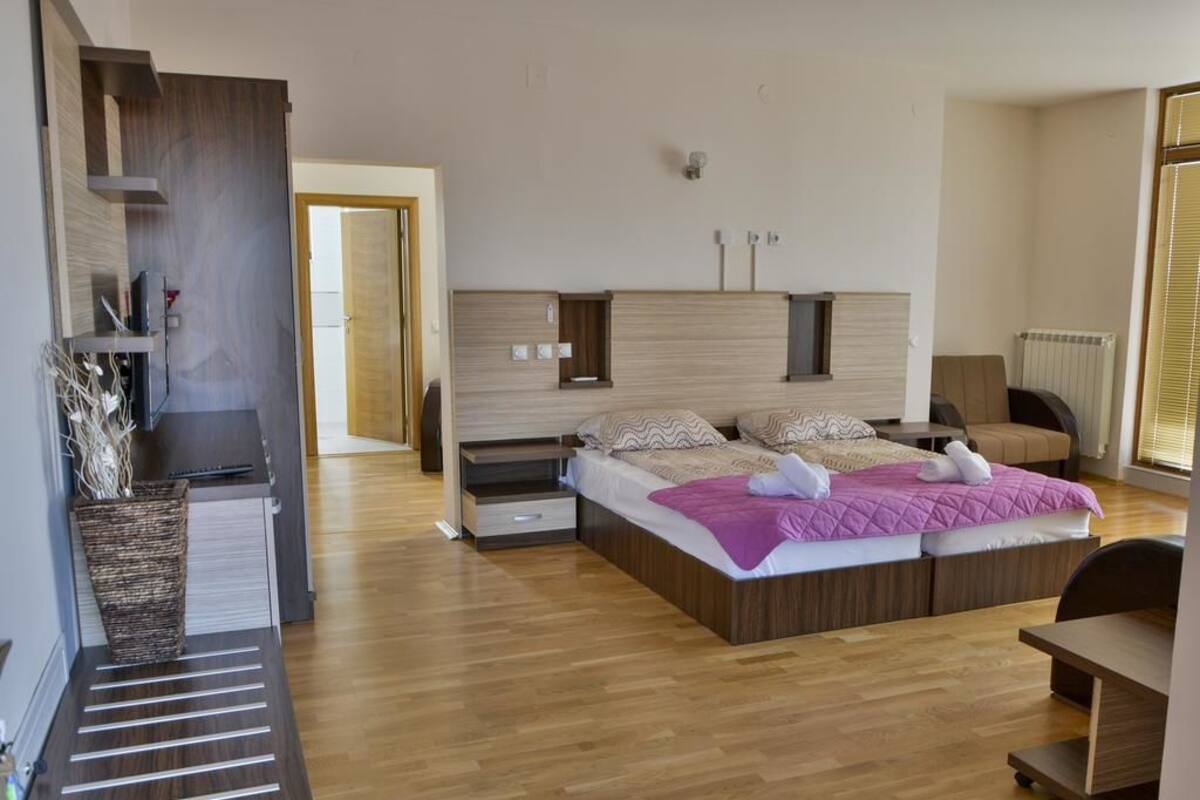 Un dormitorio moderno con una cama grande, estanterías empotradas, un escritorio y un radiador.