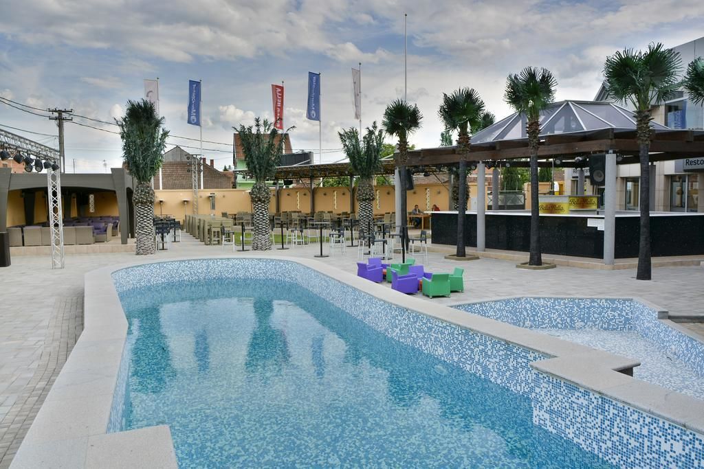 A swimming pool area with lounge chairs and a covered seating area.
