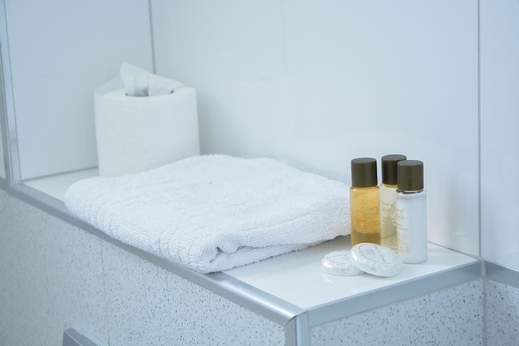 Een badkamer met een witte handdoek, een pak tissues en twee flesjes lotion op een aanrecht.