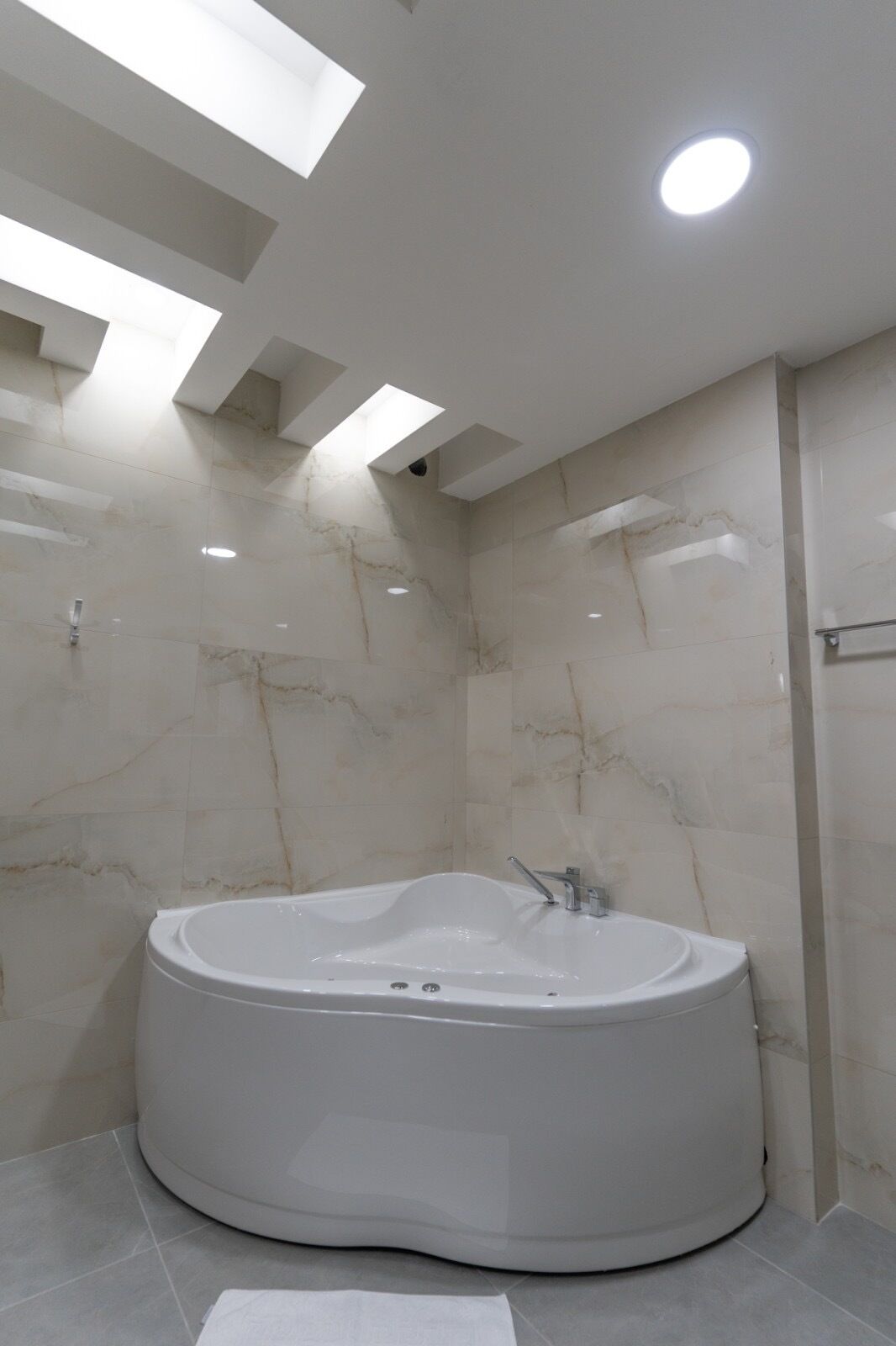 A modern bathroom with a freestanding bathtub, skylights, and marble walls.