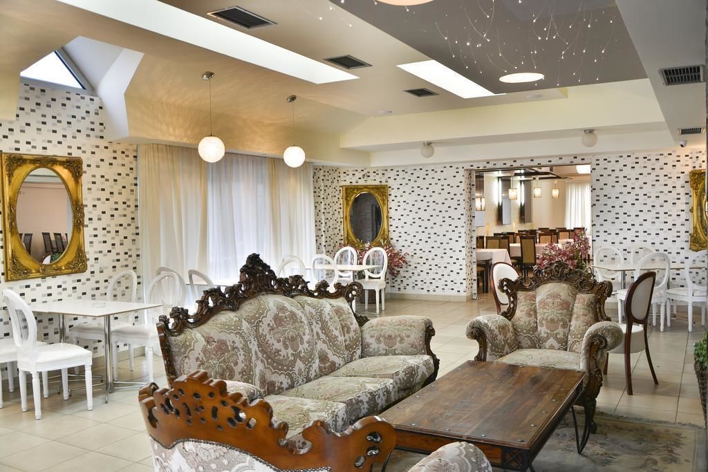 Un salón amplio con techo alto, paredes con diseño y una mezcla de muebles modernos y clásicos.